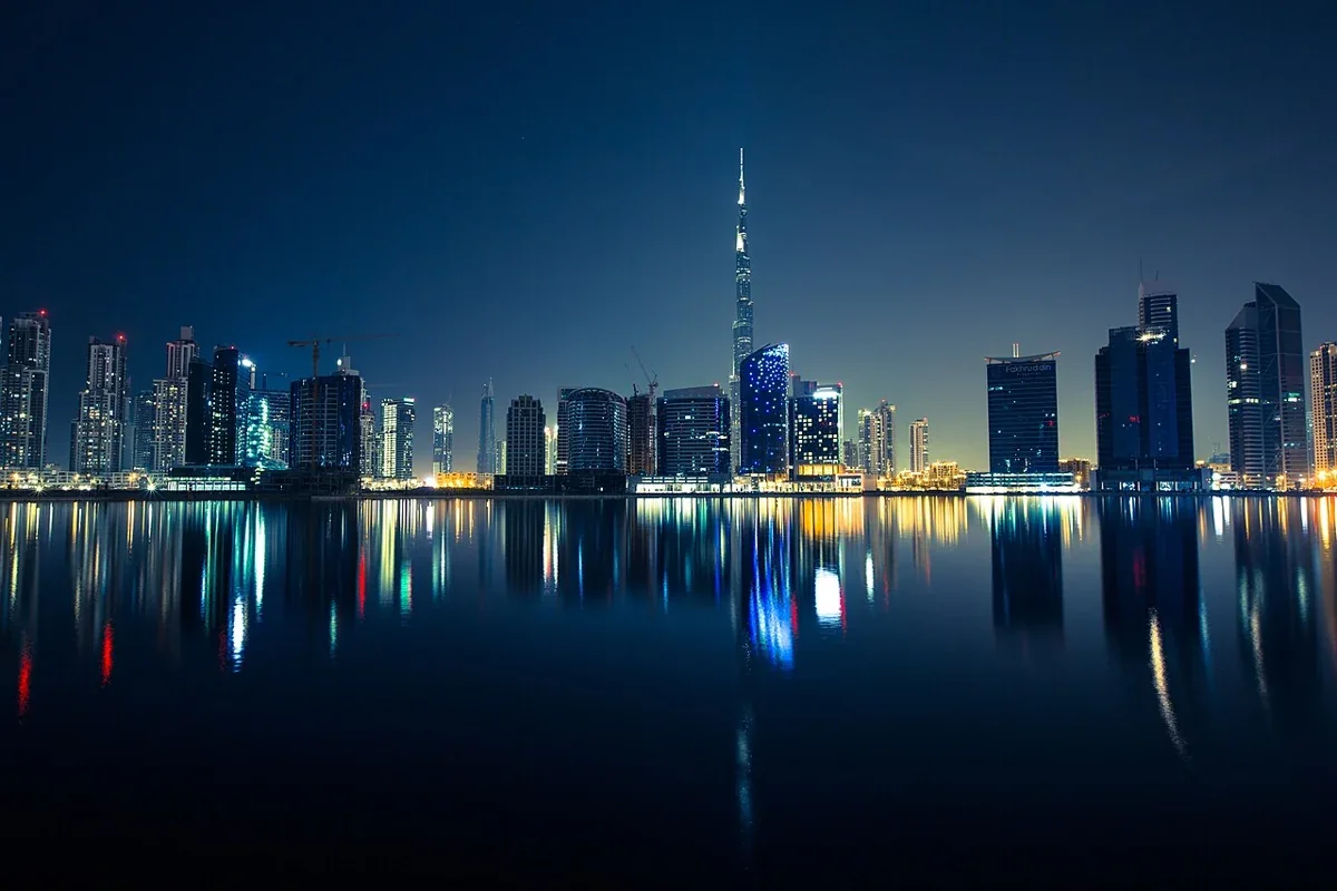 Dubai skyline and the Burj Khalifa reflected in water at night, United Arab Emirates