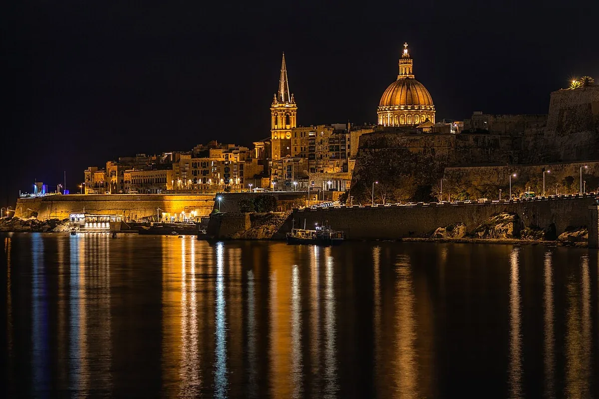 The illuminated Valletta skyline reflected in Marsamxett Harbour at night, Malta